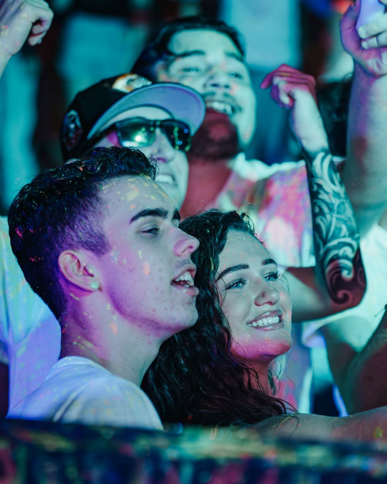 Young couple smiling close together in a lively night crowd, Panama City Beach