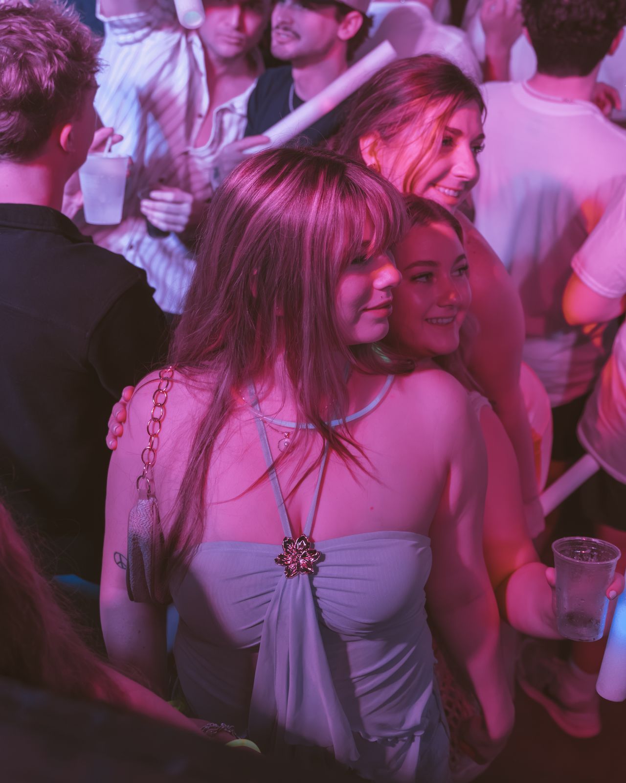Friends Embracing Pink Lights Friends embracing under pink club lights with drinks in hand, Panama City Beach