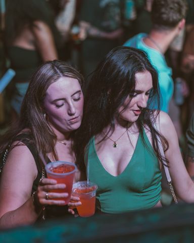 Two Friends Holding Drinks Two friends holding drinks and leaning together at a night party, Panama City Beach