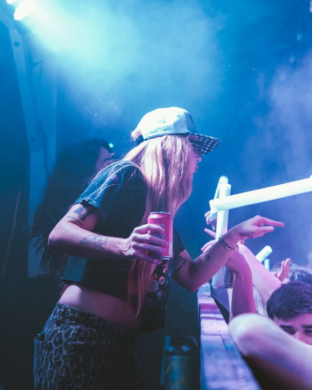 Woman in a white cap holding a drink under purple stage lighting, Panama City Beach